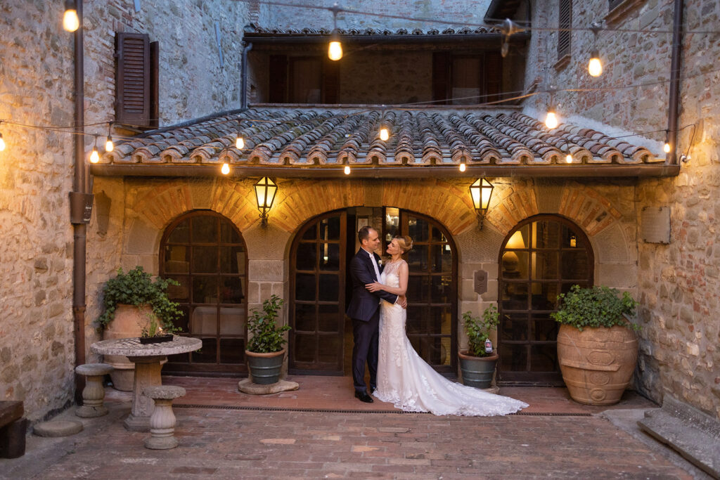 Couple outside the stone entrance at The Castel Rigone Wedding Estate at dusk.