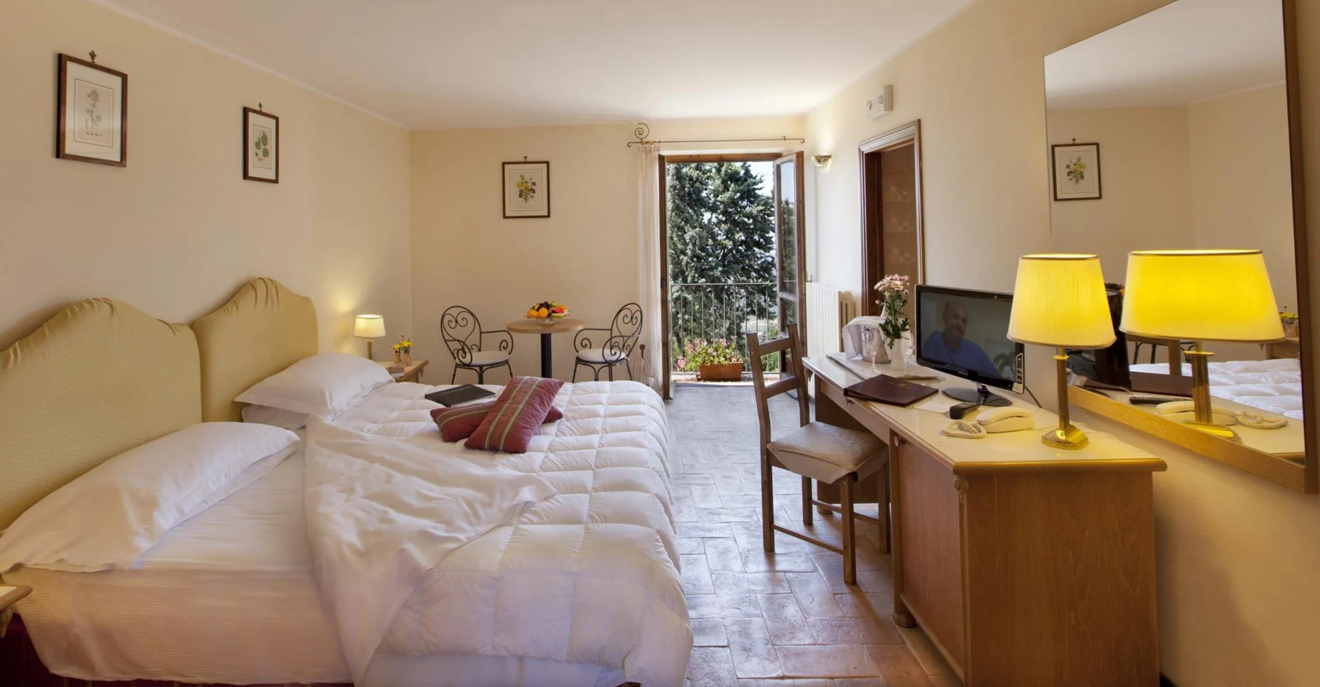 Guest bedroom with pale furnishings and a glazed door at Relais La Fattoria