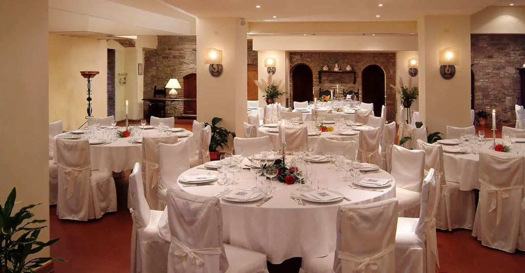 Round reception tables inside the stone-arched hall at Relais La Fattoria